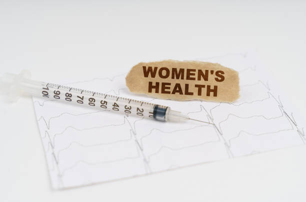Medicine and health concept. On the table is a cardiogram, a syringe and paper with the inscription - WOMENS HEALTH