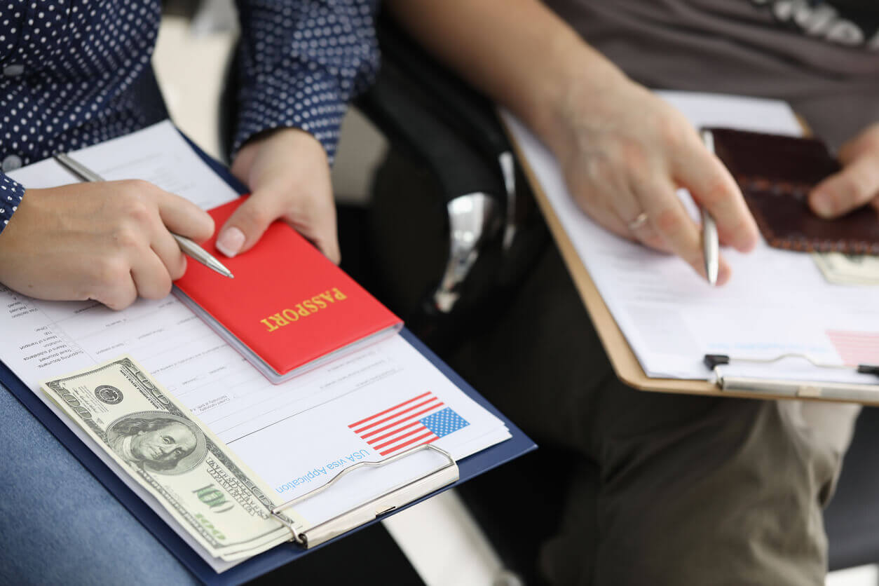 Image of two individuals whose faces are blurred out filling out a form for Immigration Medical Examination.